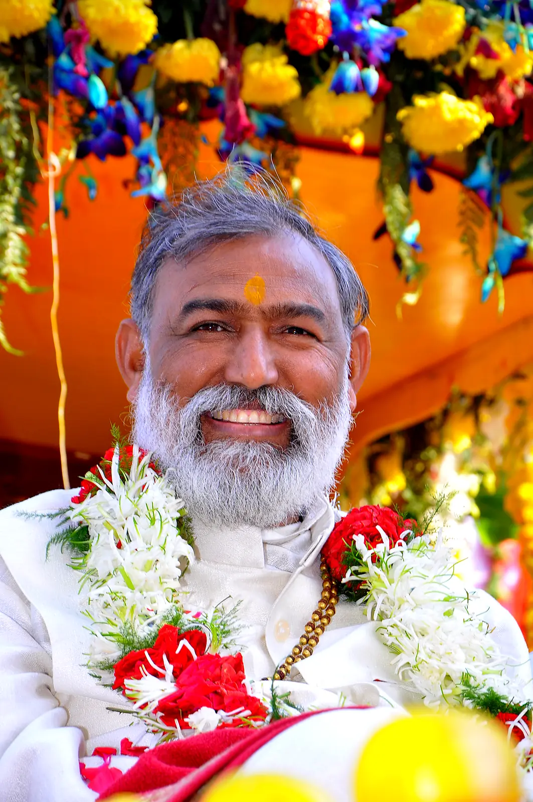 Guruji with garlands and tilak on a festival day