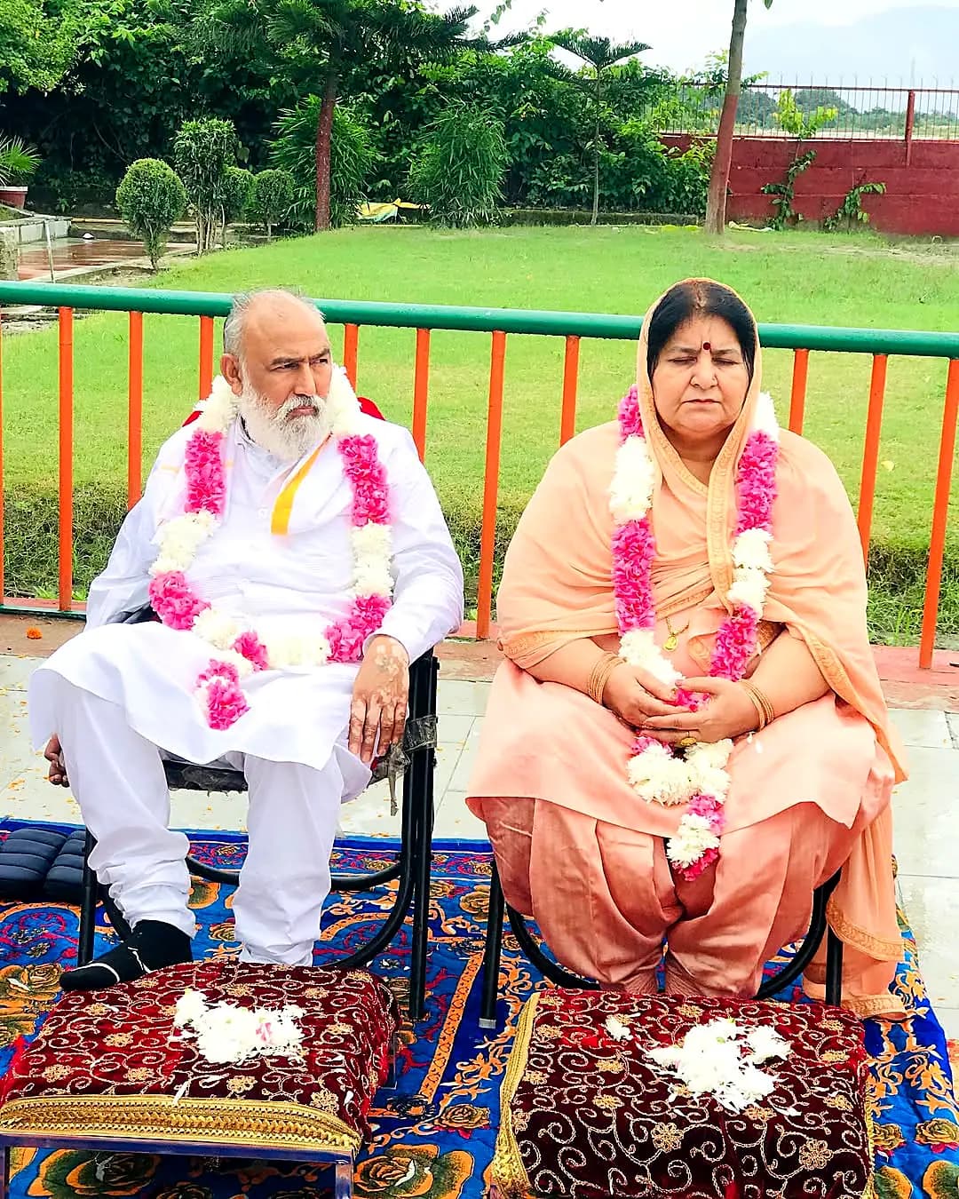 Guruji and Guru Maa garlanded in the ashram garden