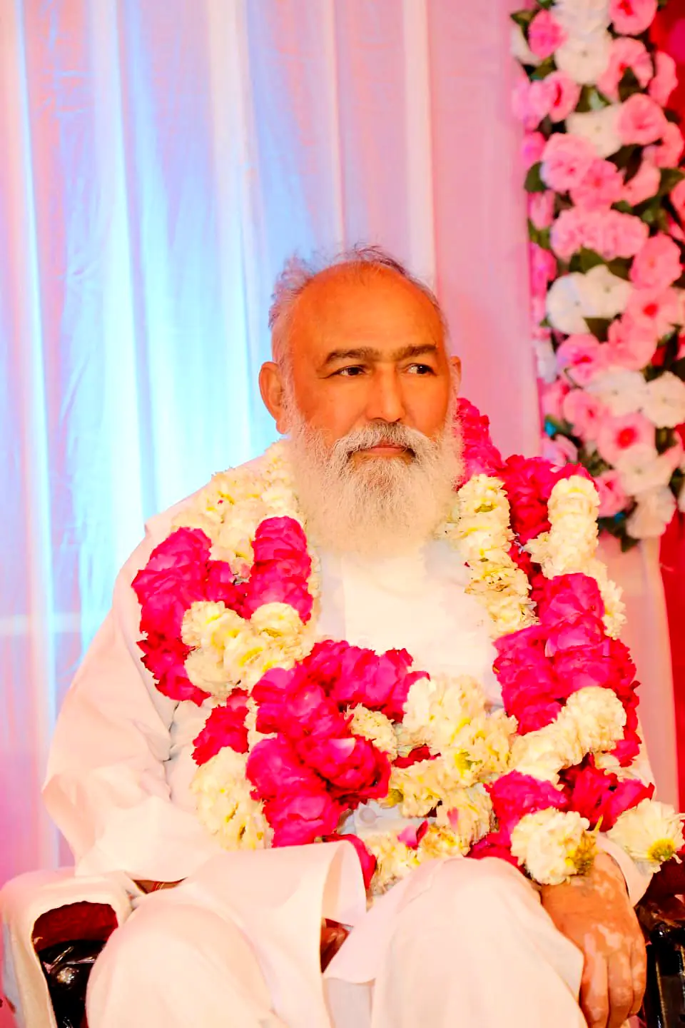 Guruji adorned with pink and white garlands